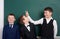 Elementary school boy friends, fooling around near blank chalkboard background, dressed in classic black suit, group pupil, educat