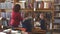 Elementary school girls, librarian or teacher stand at the shelves with books in the library