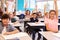 Elementary school kids in a classroom raising their hands