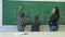 Elementary school. Little schoolgirls writing numbers on green chalk board in classroom