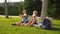 Elementary school students boys and a girl sat down together under a tree for lunch with sandwiches.