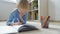 Elementary student boy doing homework at home. Child learning to count, solves arithmetic examples, doing exercises in workbook.