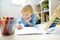 Elementary student boy doing homework at home. Child learning to count, solves arithmetic examples, using abacus. Math tutorial.