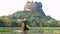 Elephant spraying water with trunk, Lion Rock Fortress behind