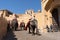 Elephants crossing narrow mountain path in front of the amber fort in jaipur with people roaming around enjoying the