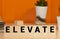 Elevate word written on wood block