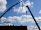 Elevated crane booms on a construction site, against a blue sky