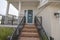 Elevated entrance of a house with wooden stairs and metal railings