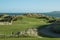 Elevated links par 3 golf hole with large sand dunes and ocean horizon