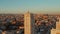 Elevated shot of town development lit by bright sunset light. Torre de Madrid historic high rise building in foreground.