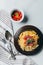elevated view of plate with pasta, kitchen towel, fork, spoon and bowl with cherry tomatoes