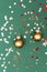 Elevated view of two Christmas golden copper decoration balls with red sequins glitter on a green background.