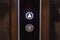 Elevator call buttons on a brown wooden panel