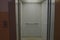 Elevator and it`s light gray interior with metal handrails and overhead lighting visible through open doors against a peach wall