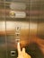 Elevator service concept. Finger pressing button in elevator.