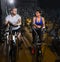 Elliptical walker trainer man and woman at black gym