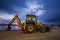 Ellow excavator with a shovel at a construction site in a beautiful twilight