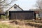 Elongated garage covered with dark corrugated metal protection in suburban family house backyard