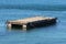 Elongated homemade makeshift old floating pier made from empty metal barrels and dilapidated narrow wooden boards