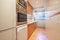 Elongated kitchen with wooden furniture, white countertop and window with cement lattice