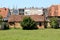 Elongated old red brick outdoor storage building with destroyed and cracked dilapidated roof tiles next to family house