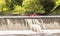 Elora, Ontario, Canada - 05 15 2022: Rowers in bright red kayaks beside waterfalls of the Grand River near community of