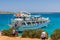 ELOUNDA, CRETE - 16 JULY 2021: Groups of tourists swim around and depart a busy day cruise boat near the town of Elounda in Crete