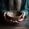 Emaciated hands hold an empty bowl against wood, depicting the reality of hunger