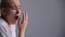 Emaciated young woman with short hair yawns on white background.