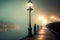 embankment in fog with lit lamp post standing by water