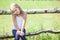 Embarrassed small girl sitting on rural fence