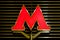 Emblem, the red letter `M` of the Moscow metro on gold polished metal background