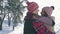 Embrace of a young cheerful couple of young people in a winter forest on a sunny day