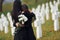 Embracing each other and crying. Two young women in black clothes visiting cemetery with many white crosses. Conception of funeral