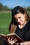 Embracing the Spring Bliss: Young Woman Captivated by a Retro Book in the Serene Park Setting