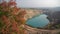 Emerald Azure lake in a flooded quarry in the shape of a heart and autumn red foliage. Oval lake in mining industrial