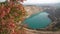 Emerald Azure lake in a flooded quarry in the shape of a heart and autumn red foliage. Oval lake in mining industrial