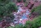 Emerald mountain stream flows through a red stone gorge in the French wilderness