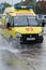 Emergency Ambulance Reanimation Medical vehicle driving on road over muddy puddle, splashing wat