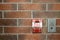 Emergency fire alarm switch on red brick wall background