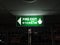 Emergency green fire exit sign, on the ceiling at night.