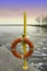 Emergency life preserver hanging on a yellow pole by an icy winter lake