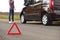 Emergency stop sign and driver near broken car on road