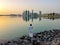 Emirati man wearing traditional cloth on the beach looking at Abu Dhabi city famous landmark at towers at sunset