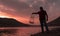 Emirdag / Afyonkarahisar - August 11 2019: Fisherman holding fishing tank and lake and pink sky in background