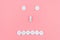 Emoticon from medical pills on a pink background. The concept of healthcare