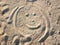 Emoticon painted on the sand. Funny physiognomy, face. Smile on the beach.