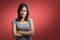 Emotion concept, Portrait of angry cute asian woman standing posing with crossed arms looking at camera with grey clothes on a red