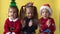 Emotion Cute Happy 3 Siblings Friends Baby Girl And Boy Applaud in Santa Suit Looking On Camera At Yellow Background