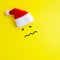 Emotion of a sad disappointed person painted on a yellow background under the red Santa Claus hat. Unhappy New Year and Christmas